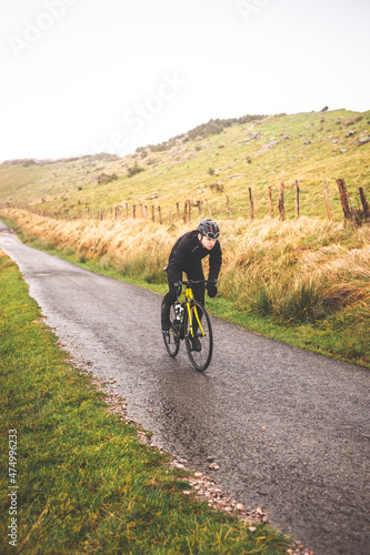 Young caucasian cyclist man climbing a hill in a foggy mountain. © Jorge Argazkiak