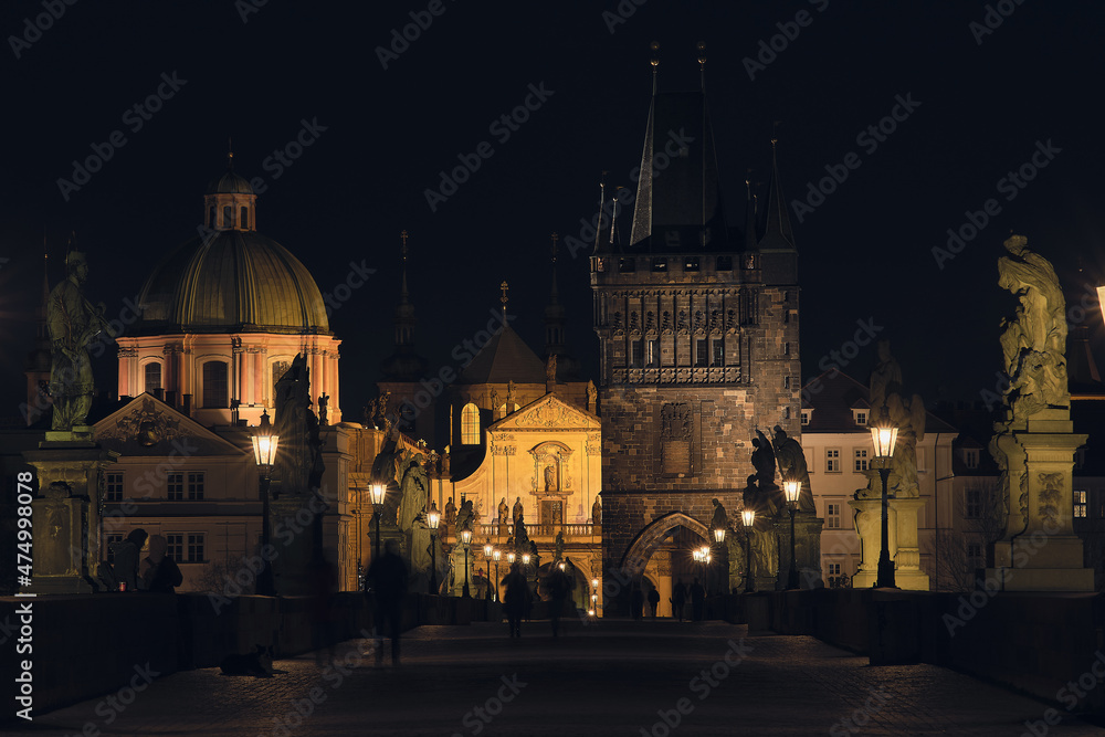 Illuminated Charles Bridge in Prague with statues at night.