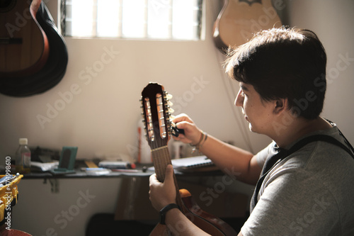 Foto latin man arranging the pins of a stringed instrument in his repair shop