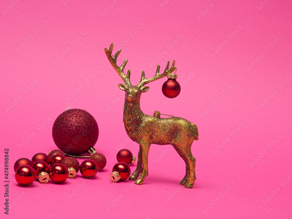 Obraz premium Xmas composition in minimal style - golden deer head with christmas bauble hanging on horns on pink background with New Year ball