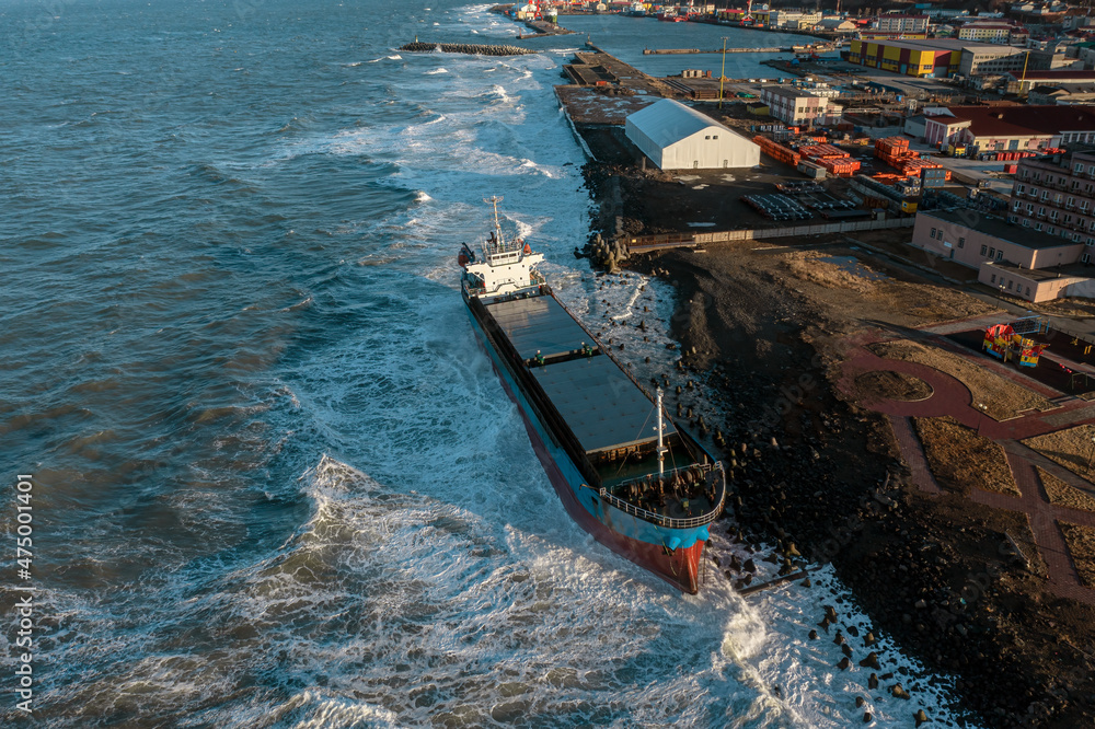 A large seagoing vessel dry cargo ship washed ashore during a strong storm wind and ran aground. The dry cargo ship washed ashore during a sea storm. Oil spills. A sea-going cargo ship washed ashore 
