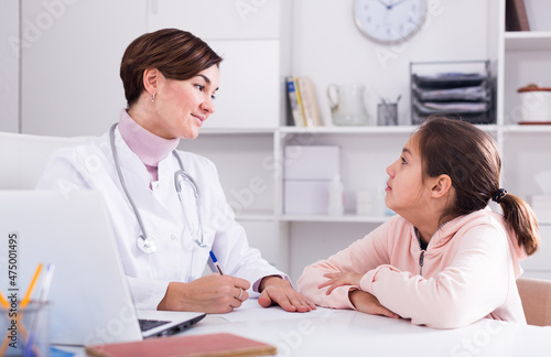 Pediatrician asks the girl about her health and fills patient s chart