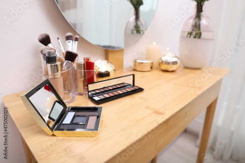 Different makeup products on wooden dressing table indoors