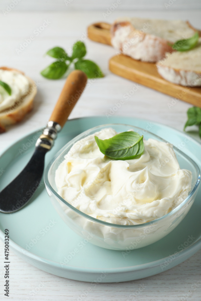 Tasty cream cheese with basil and knife on white wooden table Tasty cream cheese with basil and knife on white wooden table