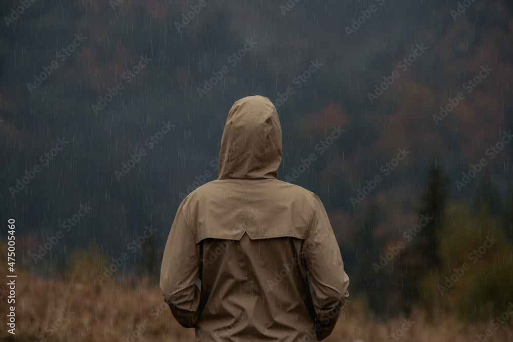 Woman in raincoat enjoying mountain landscape under rain, back view Woman in raincoat enjoying mountain landscape under rain, back view