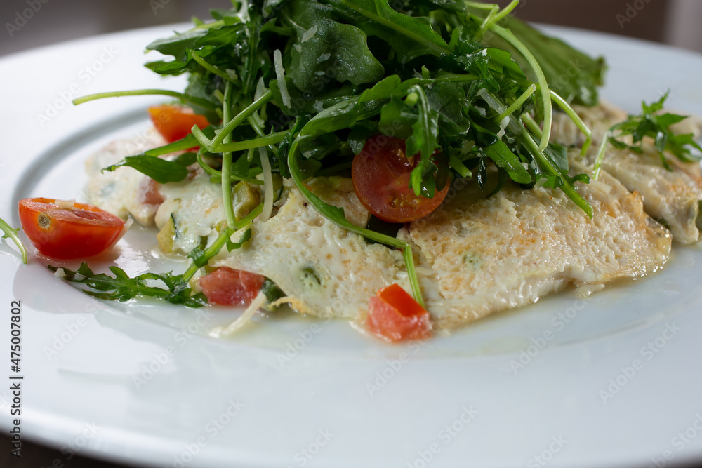 A closeup view of a white egg omelet, with an arugula salad. A closeup view of a white egg omelet, with an arugula salad.