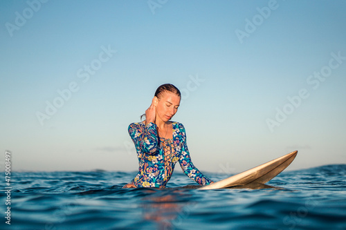 Photography Portrait of blond surfer girl on white surf board in blue ocean pictured from the water in Encuentro beach in Dominican Republic
