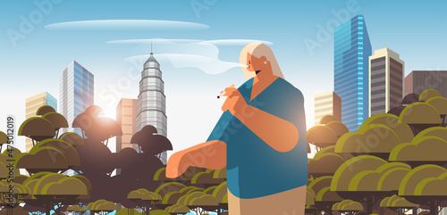 woman walking in park and smoking cigarette bad habits unhealthy lifestyle nicotine addiction no smoking concept