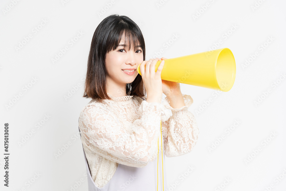 白い背景の前に立って応援するレースのブラウスを着た若い女性