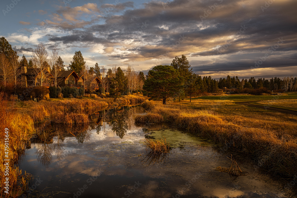  2021-12-14 THE DESCHUTED RIVER RUNNING THROUGH SUNRIVER OREGON WITH A CLOUDY SKY AND GOLDEN HOUR LIGHTING