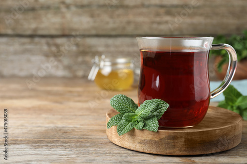 Cup of hot aromatic tea with mint on wooden table. Space for text