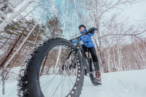 Fat bike in winter. Fat biker riding bicycle in the snow in winter. Close up action shot of fat tire bike wheels in the snow. Woman living healthy winter sports lifestyle