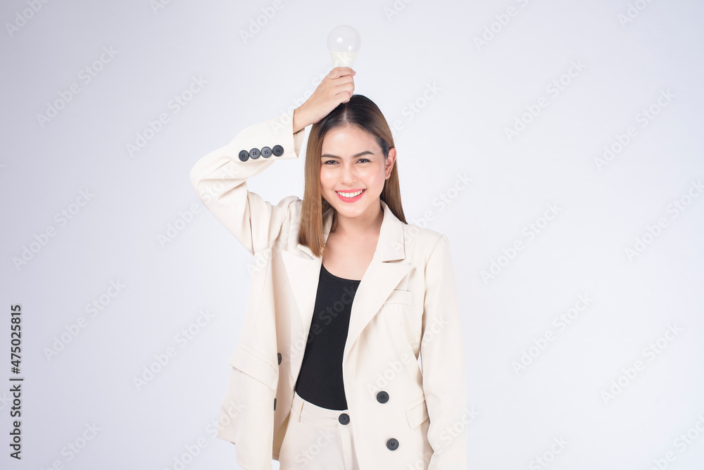 A young businesswoman is holding Light bulb wearing suit over white background studio A young businesswoman is holding Light bulb wearing suit over white background studio