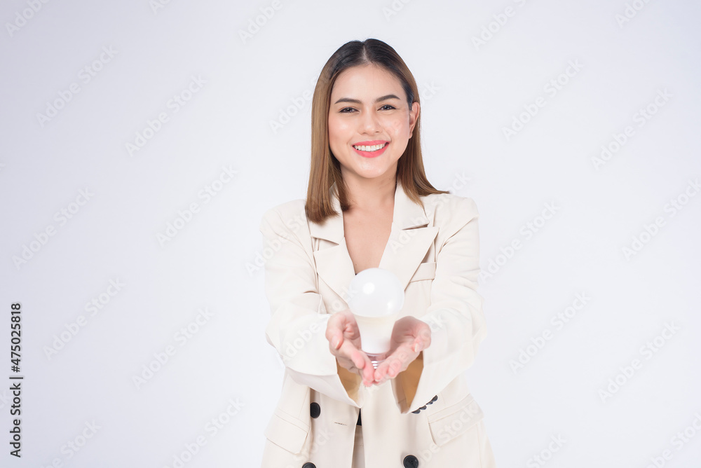 A young businesswoman is holding Light bulb wearing suit over white background studio A young businesswoman is holding Light bulb wearing suit over white background studio