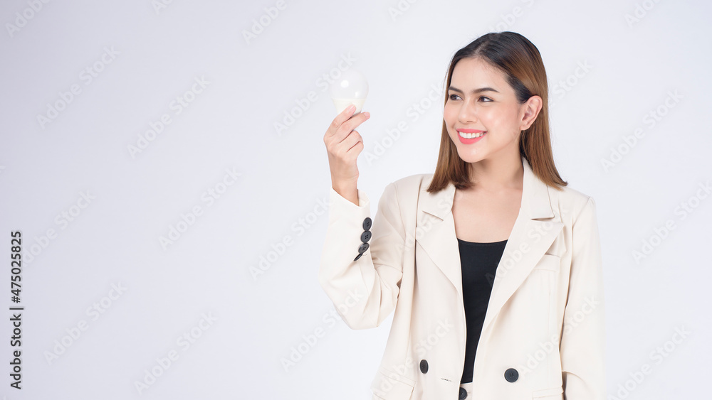 A young businesswoman is holding Light bulb wearing suit over white background studio A young businesswoman is holding Light bulb wearing suit over white background studio