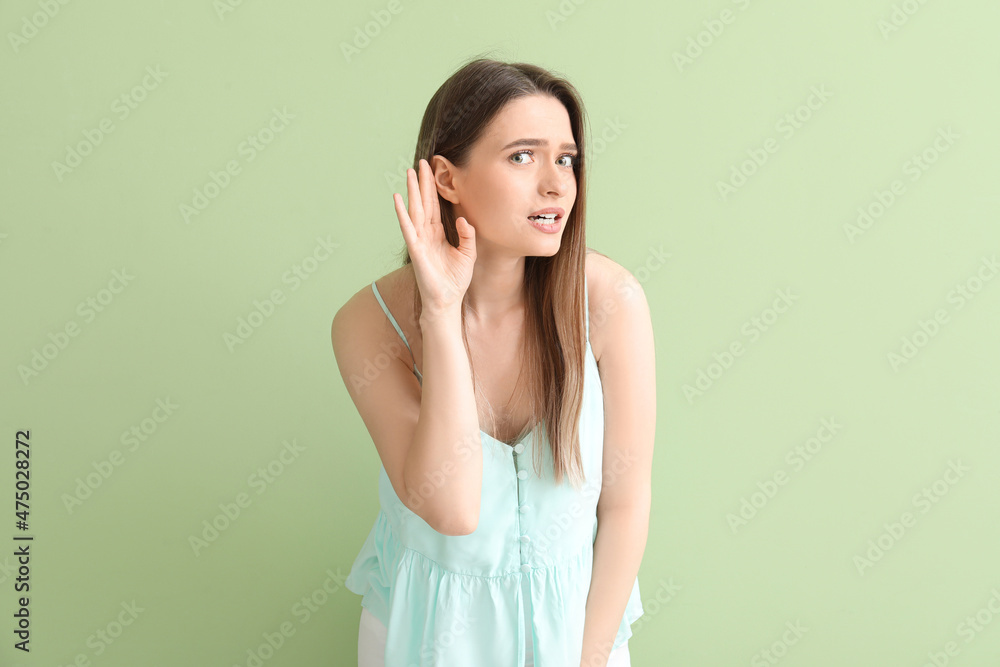 Young woman trying to hear something on color background Young woman trying to hear something on color background