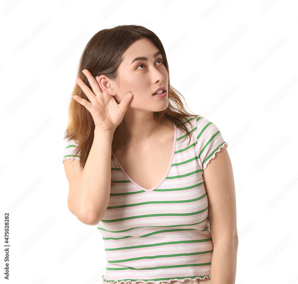 Young Asian woman trying to hear something on white background Young Asian woman trying to hear something on white background