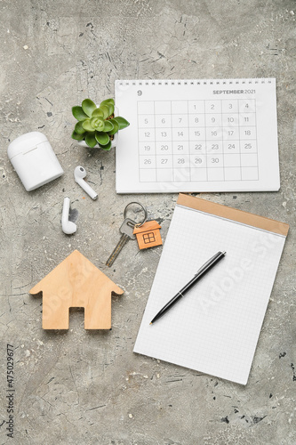 Wooden house with key, notebook, earphones and computer keyboard on grunge background