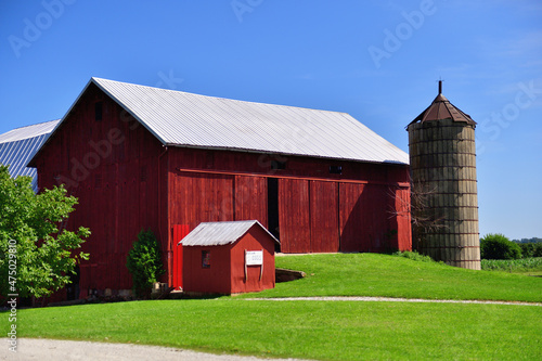 A red barn in the midst of Amish country in northeastern Indiana. The old wooden red barn standout within the green of a mid-summer day.