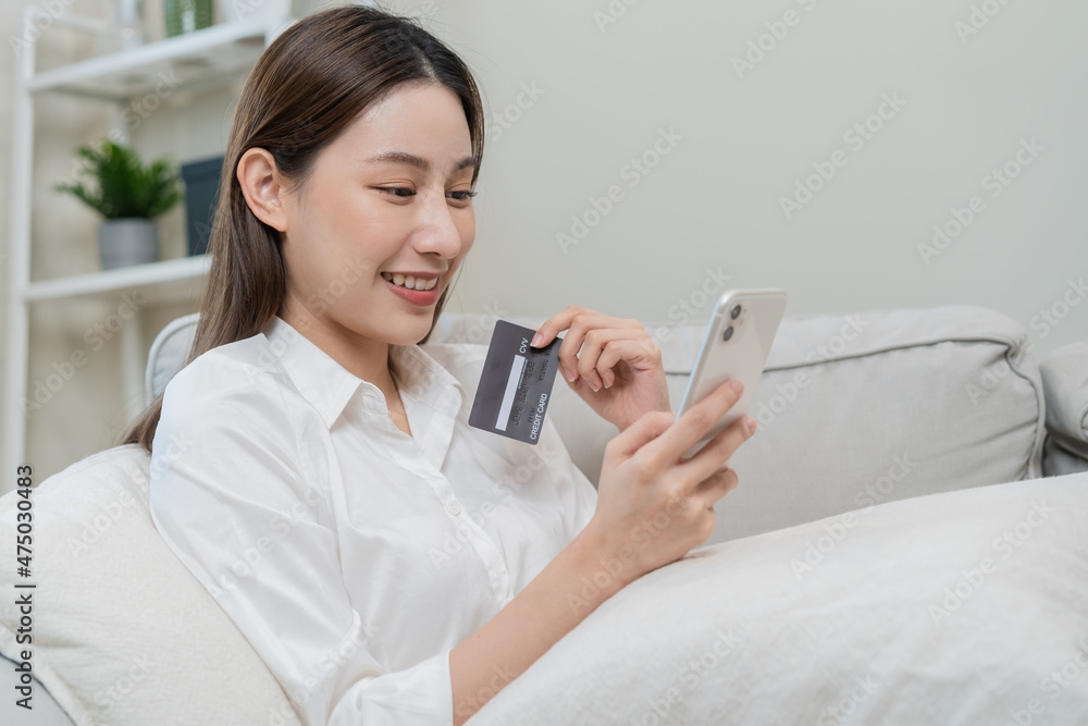 Internet banking, Online shopping at home, happy asian young woman, girl hand in holding credit card, using smartphone, mobile spending money with purchase, pay on store at home. Shopaholic e-commerce Internet banking, Online shopping at home, happy asian young woman, girl hand in holding credit card, using smartphone, mobile spending money with purchase, pay on store at home. Shopaholic e-commerce