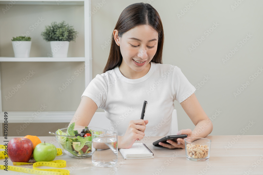 Diet, Dieting pretty asian young woman working, write diet plan right nutrition with eat fresh vegetables salad is food for good health not eat junk food. Nutritionist female, Weight loss of healthy. Diet, Dieting pretty asian young woman working, write diet plan right nutrition with eat fresh vegetables salad is food for good health not eat junk food. Nutritionist female, Weight loss of healthy.