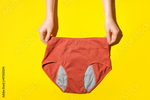 Tableau sur toile Woman holding period panties on yellow background