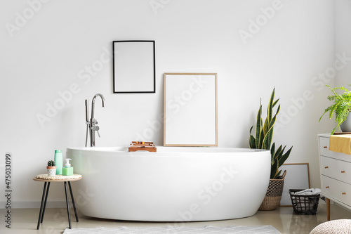 Interior of light bathroom with blank frames