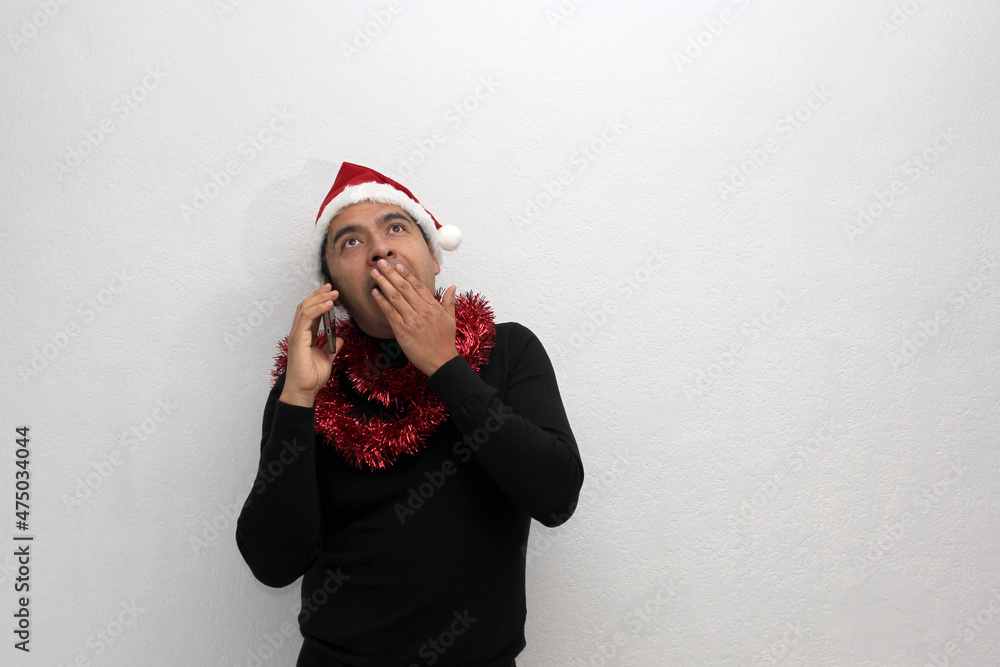 Latino adult man with Christmas hat and red garland as scarf uses his cell phone to call his family with happy video call and excited to celebrate Christmas
Latino adult man with Christmas hat and red garland as scarf uses his cell phone to call his family with happy video call and excited to celebrate Christmas