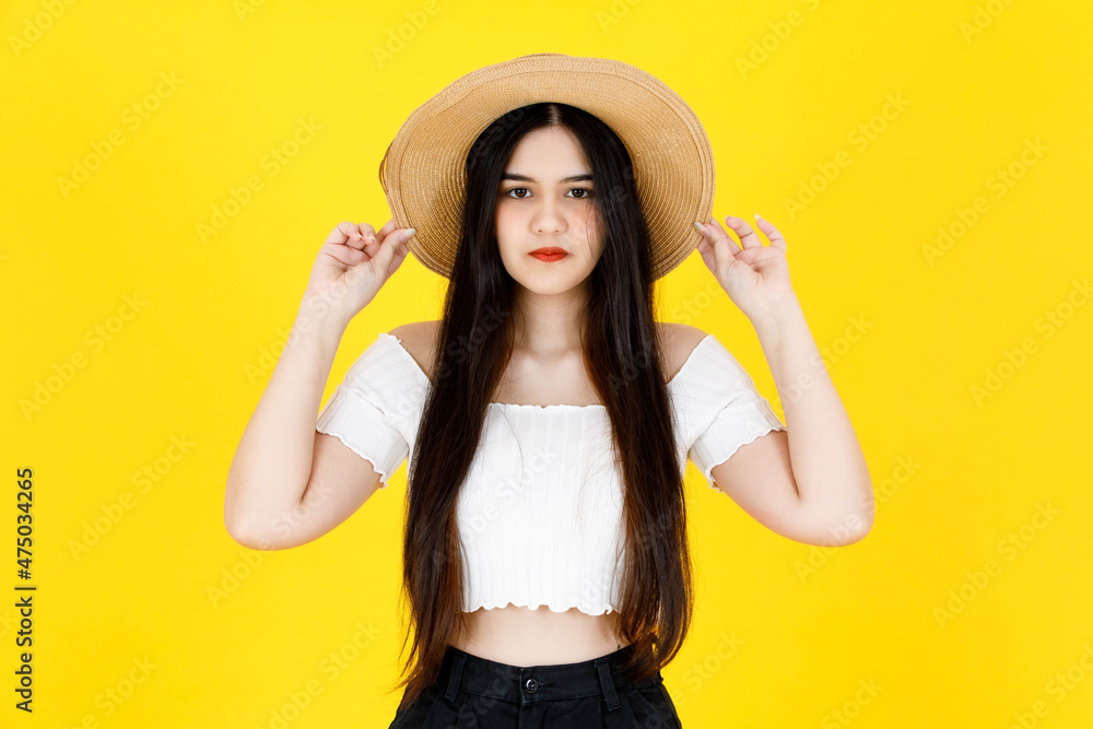 Portrait studio shot of Asian young beautiful sexy long black hair female model wearing crop top outfit dental care braces standing smiling holding hand touching adjusting hat on yellow background Portrait studio shot of Asian young beautiful sexy long black hair female model wearing crop top outfit dental care braces standing smiling holding hand touching adjusting hat on yellow background