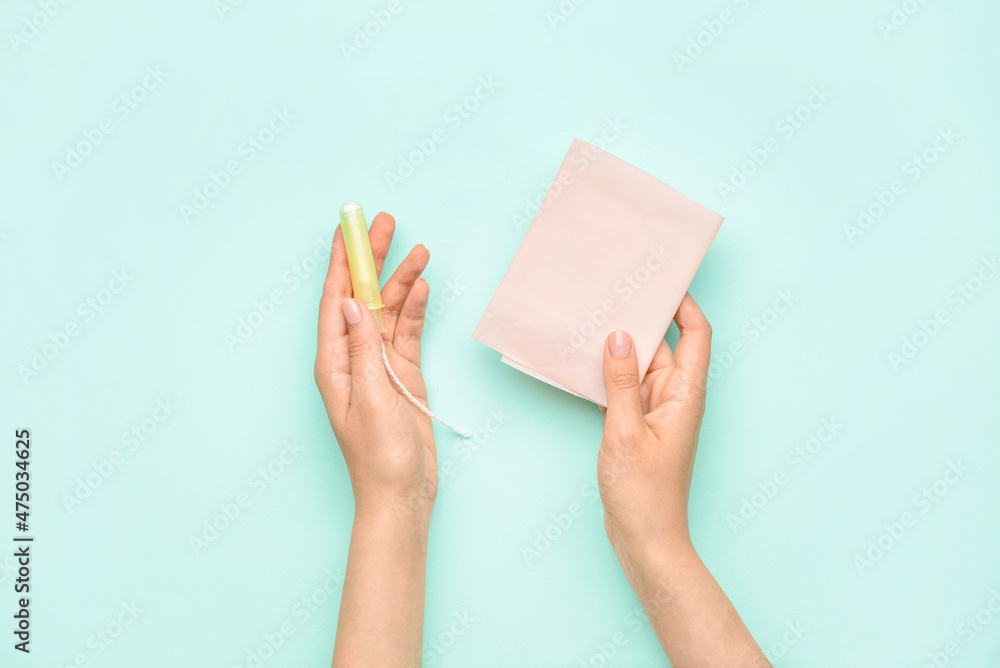 Female hands with menstrual pad and tampon on color background Female hands with menstrual pad and tampon on color background