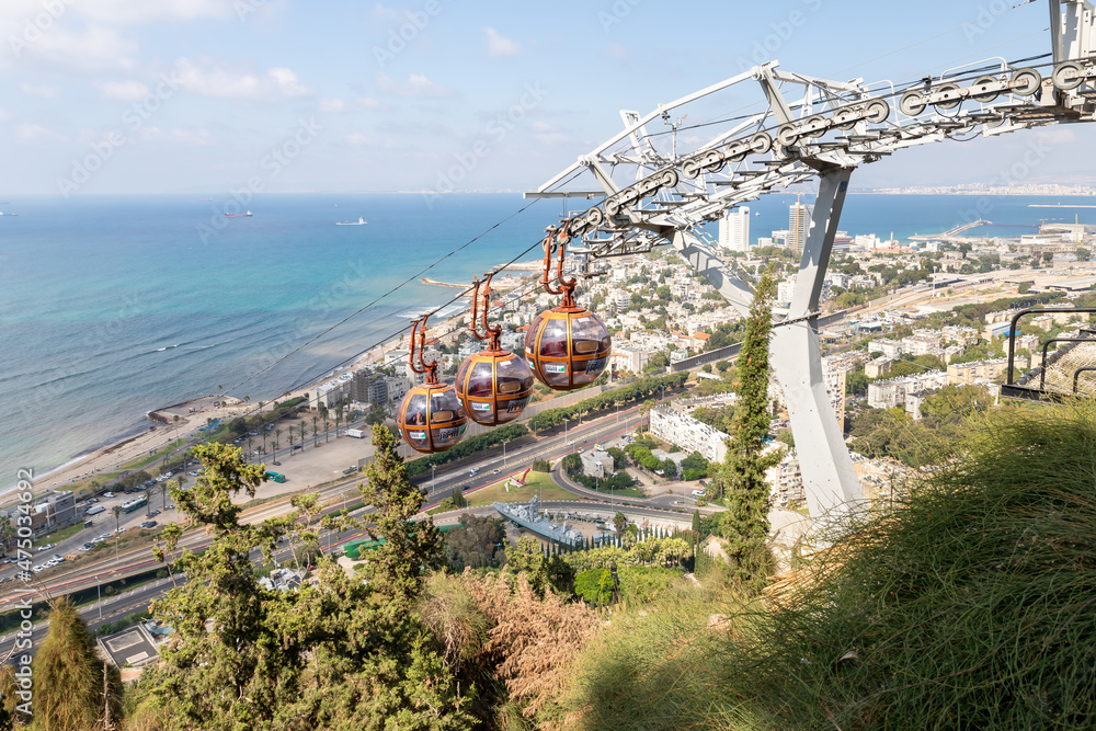 The cabins of the cable car move up towards the upper station on Mount Carmel against the background of the lower city and the Mediterranean Sea in Haifa in northern Israel