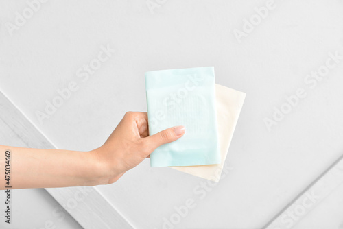 Female hand with menstrual pads on light background