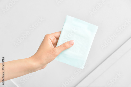 Female hand with menstrual pad on light background