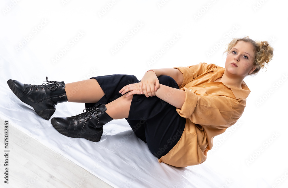 Obraz premium Studio girl. The model is posing for the camera. model poses in a shirt and trousers sporty style. street image, hooligan, casual look. isolated white background.. model plus, fat overweight girl