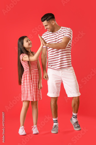 Man and his little daughter giving each other high-five on color background