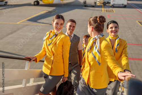 Tela Cheerful airline workers walking up plane boarding stairs