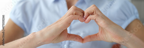 Woman shows heart hand gesture of love closeup