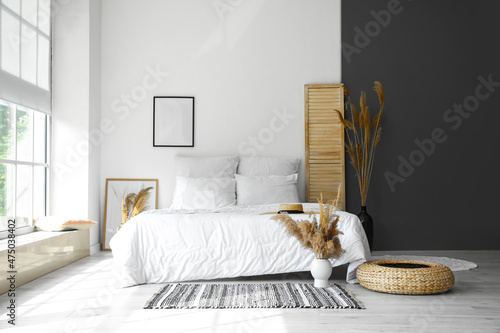 Interior of modern bedroom with dry reeds in vases