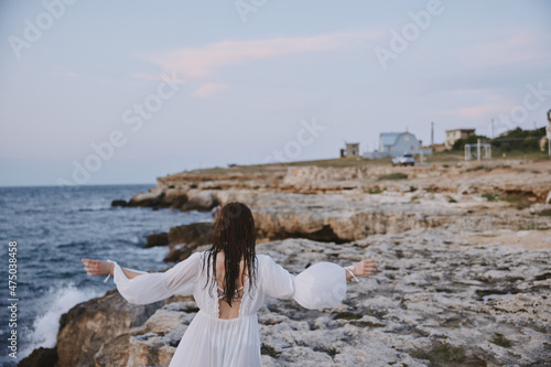 Woman in white dress with wet hair walking along the beach