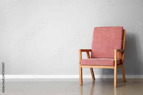 Pink wooden armchair near light wall