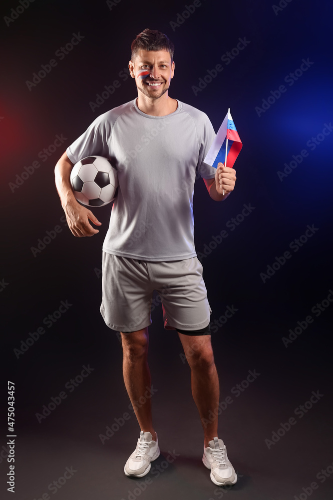 Football fan with ball and flag of Russia on dark background Football fan with ball and flag of Russia on dark background