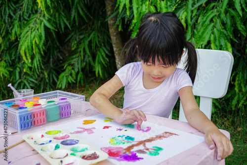 Happy Asian cute girl doing Fingerpaint, Soft Focus. Painting is play therapy for ADHD kids (Attention deficit hyperactivity disorder),can be used to address emotional problems.