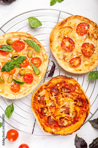 Grid with delicious mini pizzas on light background