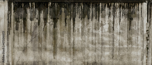 Texture of grey concrete wall with dark water and oil marks running vertically down and many marks and lines