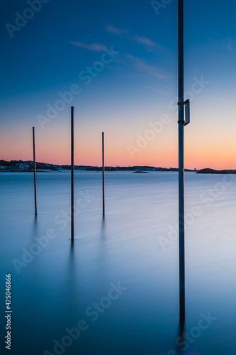 Poles standing in water at sunset © Mikael