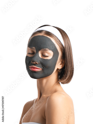 Young woman with activated charcoal mask on her face against white background