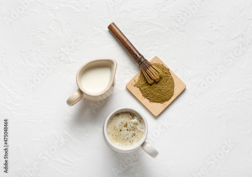 Cup of tasty hojicha latte, powder and milk on light background