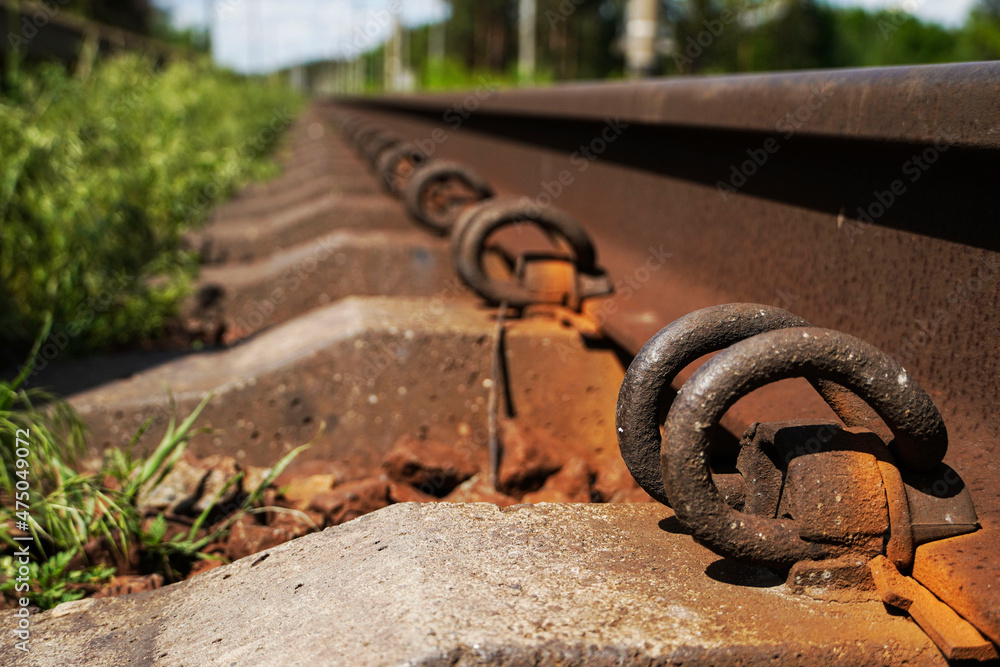 Railway tracks amidst trees. Rails and sleepers close up. Selective focus. Railway tracks amidst trees. Rails and sleepers close up. Selective focus.