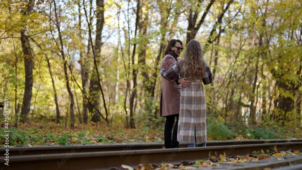 loving man and woman are embracing in autumn day, walking along forest and railway road loving man and woman are embracing in autumn day, walking along forest and railway road