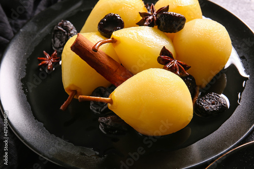 Black plate with delicious poached pears and prunes, closeup